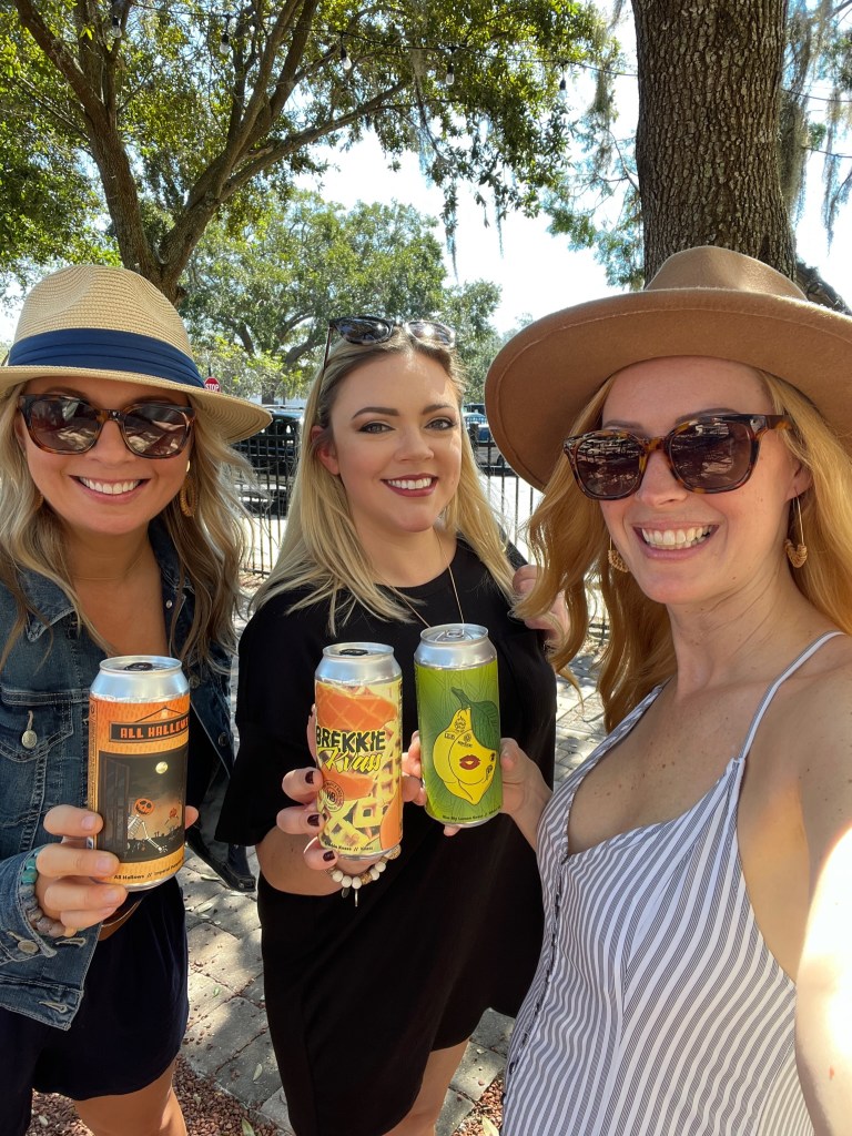 Boozy Blondes Molly Berry, @FloridaHopMama Ashley and Boozy Blondes Christina Benjamin cheersing beers at Celery City Craft Beer Garden in Sanford, Florida.